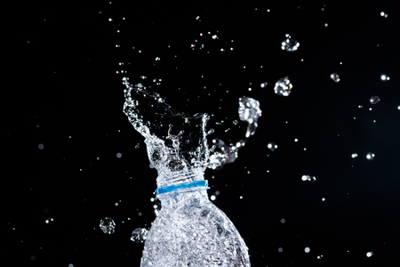 Water splashes from the bottle on black backgroundの写真素材