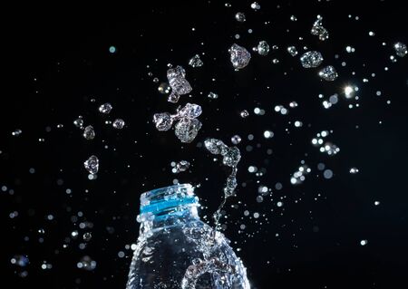 Water splashes from the bottle on black backgroundの写真素材
