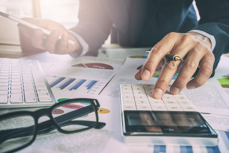 Businessman or accountant working on calculator to calculate business data concept. Accounting,investment advisor consulting situation on the financial report and planning a marketing plan at office.の写真素材