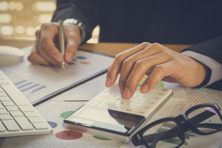 Businessman or accountant working on calculator to calculate business data concept. Accounting,investment advisor consulting situation on the financial report and planning a marketing plan at office.の写真素材