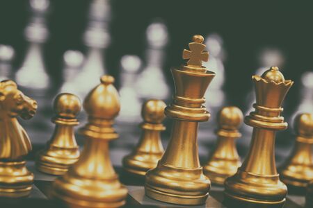The King in battle chess game stand on chessboard with black isolated background. Business leader concept for market target strategy. Intelligence challenge and business competition success play.の写真素材