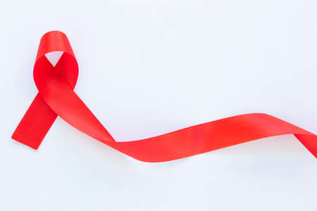 Red ribbon on white fabric background with copy space, symbol for the solidarity of people living with HIV/AIDS, and for the awareness and prevention of drug abuse and drunk driving. Health concept.の写真素材