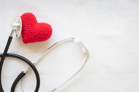 Red heart and stethoscope on white isolated background, copy space. Concept for heart health,...