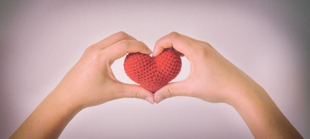 Hands gesture heart shape and hold red heart on white isolated background with copy space. Concept for love, help, kindness, donate, heart health, mental healthcare, insurance and csr business plan.の写真素材