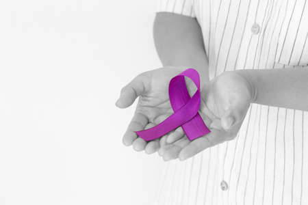 Hands holding purple or violet ribbon on white fabric with copy space. Pancreatic Cancer ,Testicular Cancer Awareness, Cancer Survivor, Leiomyosarcoma, World Cancer Day. Healthcare, insurance concept.の写真素材