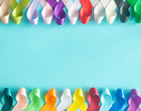 Colorful ribbons bow on pastel blue background in top view flat lay with copy space for text. World...