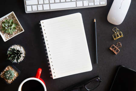Black desk office with laptop, smartphone and other work supplies with cup of coffee. Top view with...