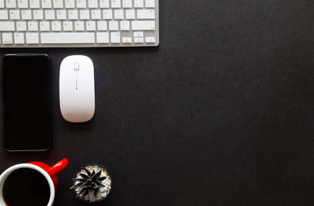 Black desk office with laptop, smartphone and other work supplies with cup of coffee. Top view with...