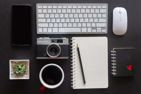 Black desk office with laptop, smartphone and other work supplies with cup of coffee. Top view with...