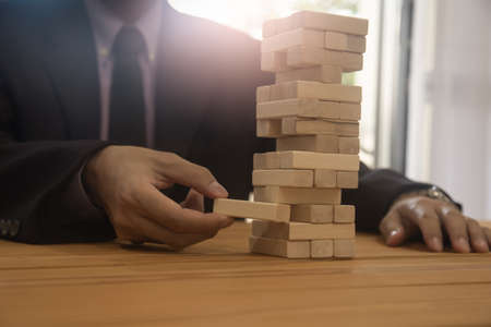 Business man gambling placing wooden block. Business concept  investment target and growth success process background present financial information planning, risk and marketing strategy analysis.の写真素材