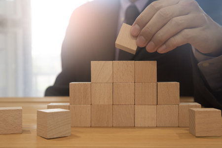 Business man gambling placing wooden block. Business concept  investment target and growth success process background present financial information planning, risk and marketing strategy analysis.の写真素材