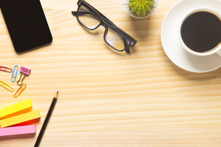 wood desk office with laptop, smartphone and other work supplies with cup of coffee. Top view with...