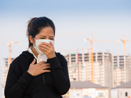 asian woman wearing face mask and coughing by pollutionの写真素材