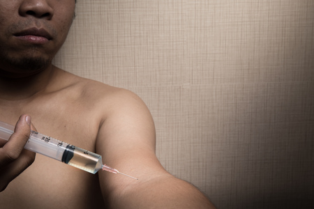 drug addiction concept with man holding syringe in handの写真素材
