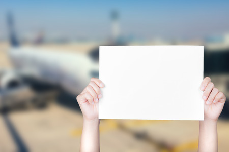 hand holding blank paper with airplane blurred backgroundの写真素材