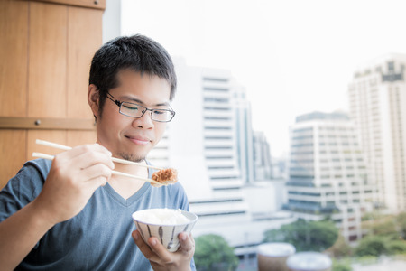 asian man eating lunch with hand holding chopstickの写真素材