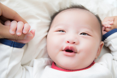 smiley asian baby boy wearing white jumpsuitの写真素材