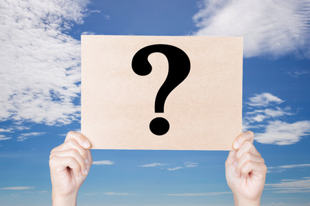 hand holding question mark sign on blue sky backgroundの写真素材