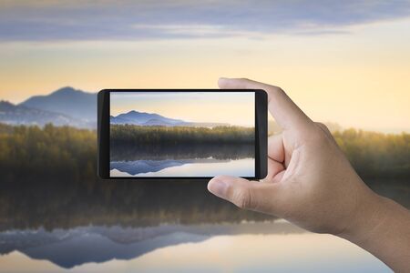 hand holding 3d rendering mobile phone taking photoの写真素材