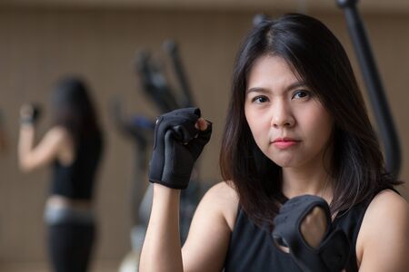 young asian woman wear gloves workout in gymの写真素材