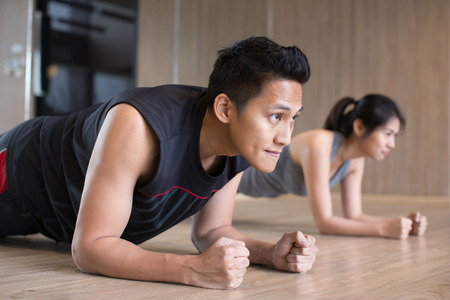 young asian couple doing plank in gymの写真素材