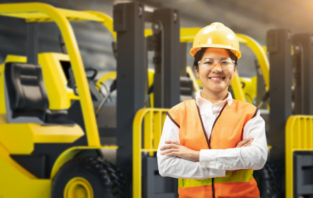 Asian engineer or technician wear safety helmet and reflective vest with forklift trucksの写真素材