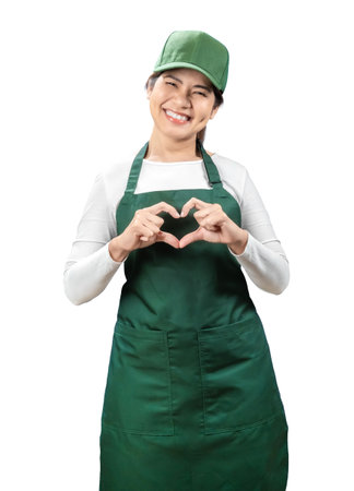 Asian seller wear green apron and green cap smiling and show heart sign isolated on whiteの写真素材