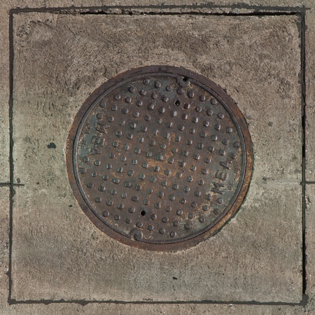 Rustic grunge storm drain manhole cover in concreteの写真素材