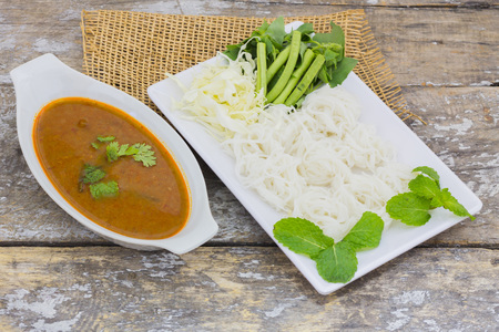 Vermicelli solution (Noodles) and fish curry coconut milk with vegetable on brown cloth backgroundの写真素材