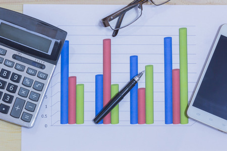 Calculator, phone,pen and glasses on financial graph, business concept.