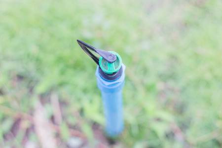 Backlit sprinkler spraying water splashed on the grass for moisture and growing in a garden.の写真素材