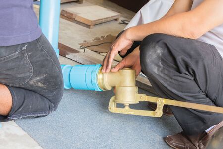 Plumbing building contractor installing plastic drain pipe in the floor section for a luxury custom...