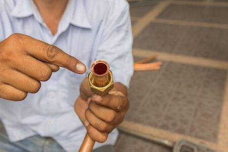 Air mechanic is working to fix the air conditioner.の写真素材