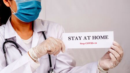 A doctor is holding Stay at home sign to motivated people to stay safe at home.  protect from Coronavirus or Covid-19 epidemicの写真素材
