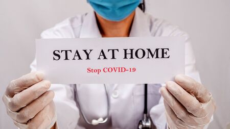 A doctor is holding Stay at home sign to motivated people to stay safe at home.  protect from Coronavirus or Covid-19 epidemicの写真素材