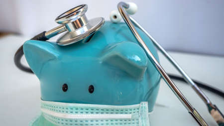 Stethoscope and Piggy Bank Wearing Protective Medical Face Mask, isolated on white background.の写真素材