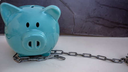 piggy bank in chain and log, isolate in black background, protecting saving money concept, copy...