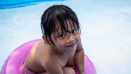 Little child is relaxing in small pool to release the heat in summer at home. Happy child, happy family, healthy family, childhood concept.の写真素材