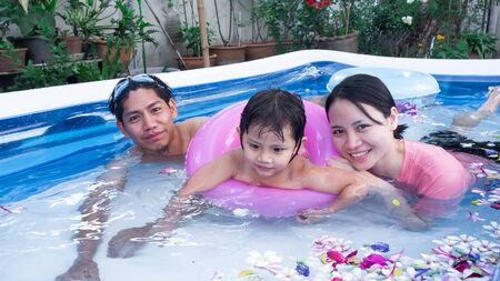Family are relaxing in a small pool to release the heat in summer at home. flowers, ball, Happy child, happy family, healthy family, childhood concept.の写真素材