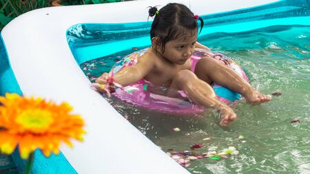 Children is relaxing in a small pool to release the heat in summer at home. Happy child, happy family, healthy family, childhood concept.の写真素材