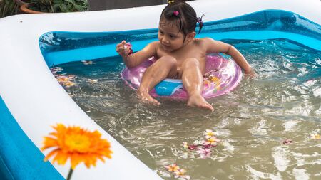 Children is relaxing in a small pool to release the heat in summer at home. Happy child, happy family, healthy family, childhood concept.の写真素材