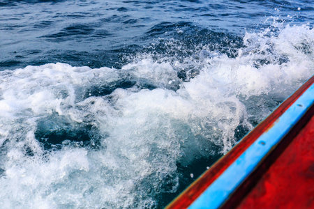 A long tail boat moving in the sea splashing water breaking the wavesの写真素材