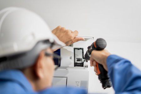 A maintenance air conditioner technician uses a drill to clean the air conditioner inside the house.の写真素材