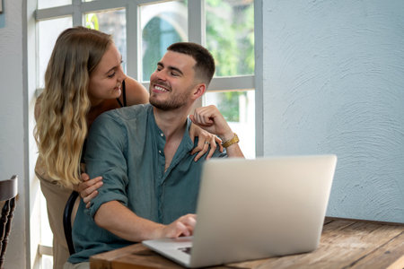 A young couple using laptop to search for online concepts in cafe smiling and laughing happily
