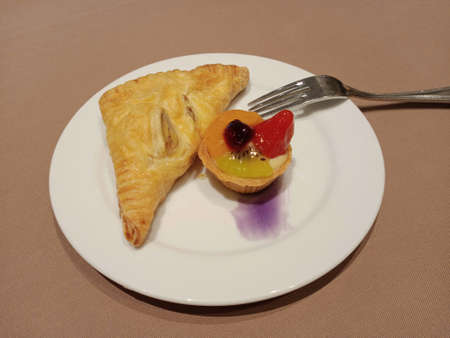 Fresh fruit tart and chicken filling croissant in a white plate on light brown background,catering...