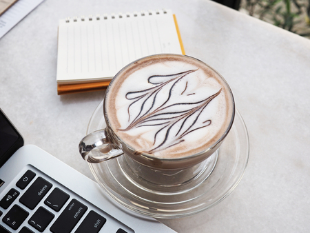 Cup of coffee with laptop, notebook and pen for workの写真素材