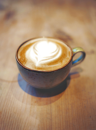 A cup of latte on a wooden table in a cafe on a cold working morningの写真素材