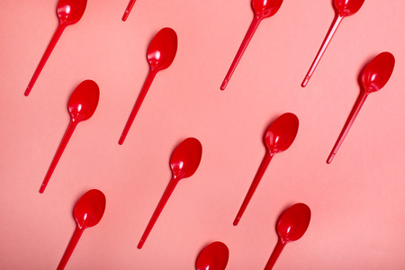 red spoons on coral color background rhythm and art