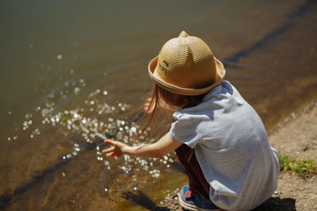 Girl sitting by the lake in the park back viewの写真素材
