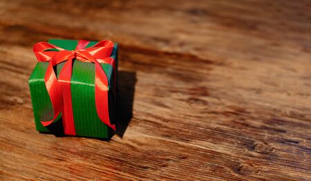 Green gift box with red ribbon on wooden backgroundの写真素材